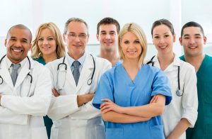 Portrait of large group of smiling doctors and surgeons standing together and looking at camera.